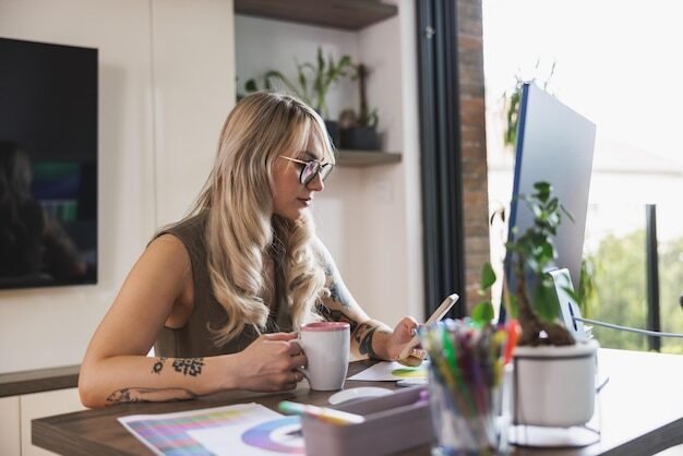 Young female freelancer using a her smart phone and taking a coffee break while working at home.